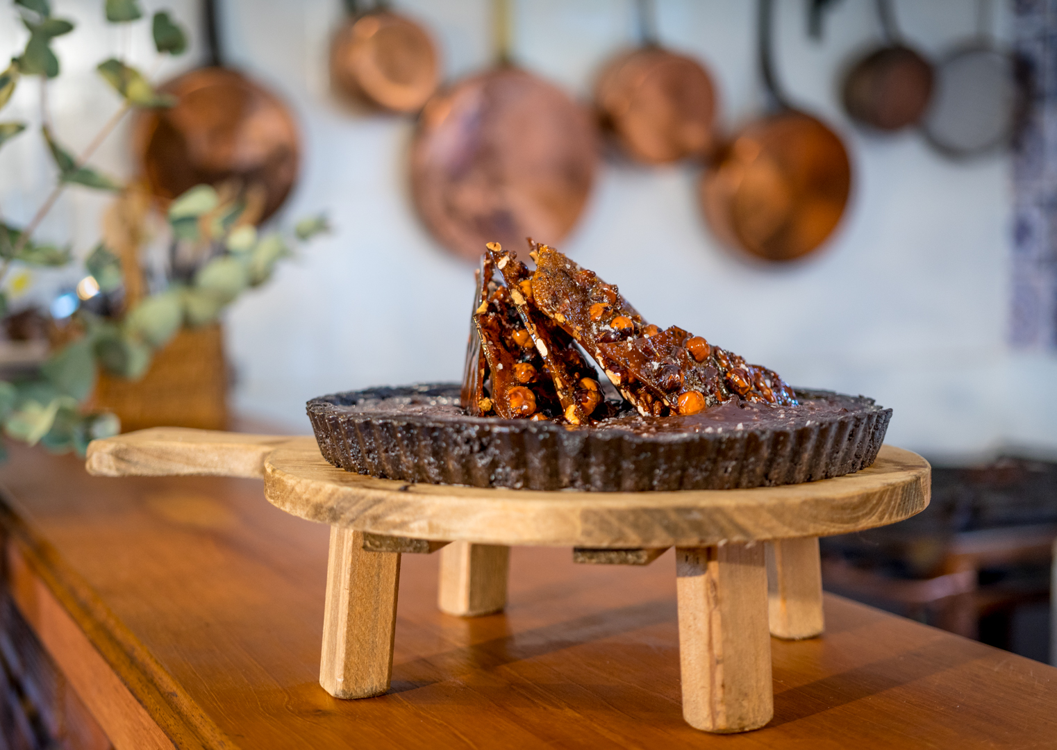 Foto de torta de chocolate com cobertura crocante em cima bandeja de madeira